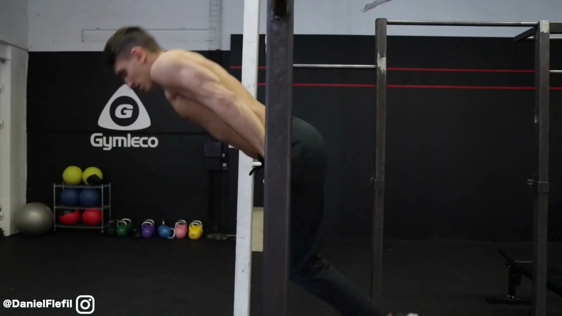 Daniel Flefil in the front support position on the bar, body horizontal, about to begin the backward roll on the bar