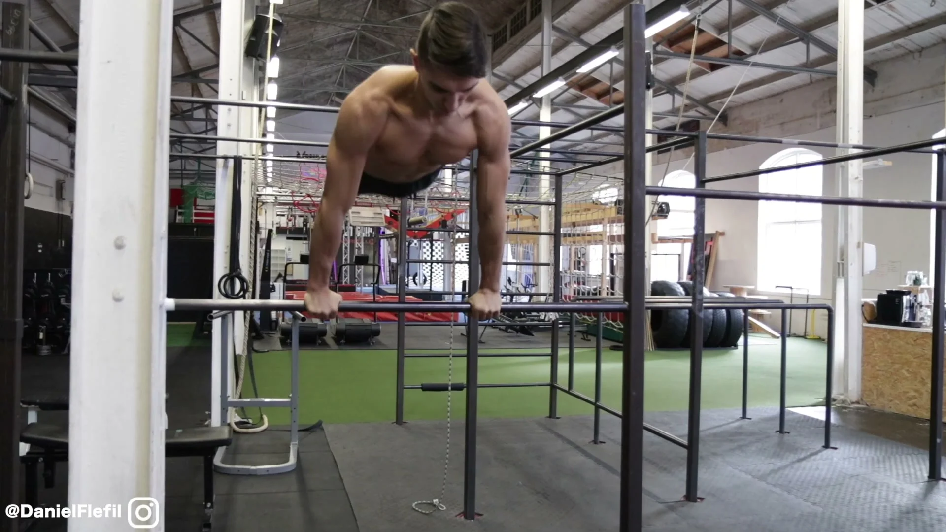 Power swing phase of the backward roll on the bar: body horizontal above the bar, arms extended, legs swept back and up