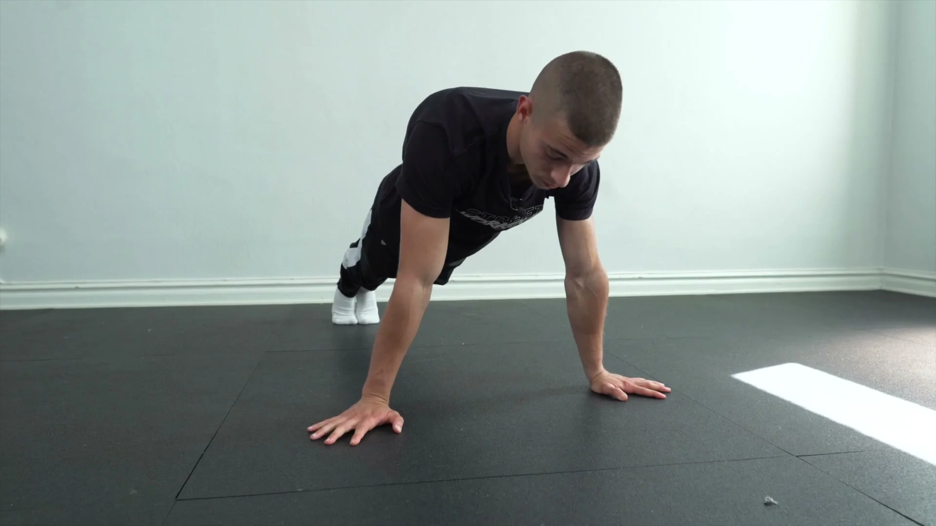 Daniel Hristov in the starting push-up lean position on the floor with elbows and biceps facing forward: straight body line and forward lean, showing the correct setup for the first explosive planche push-up tip