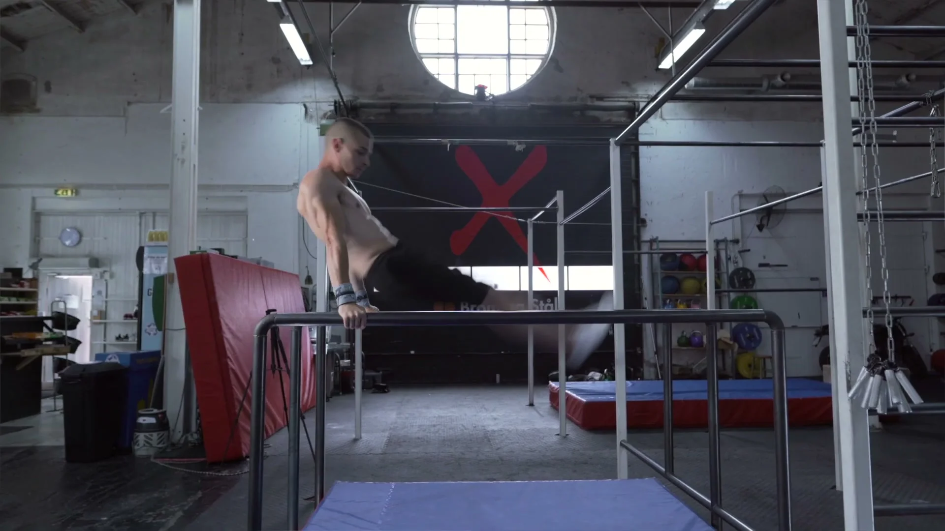 Daniel Hristov on mats beside the parallel bars after completing a front flip dismount: standing on the mat surface that should always be used during training this skill