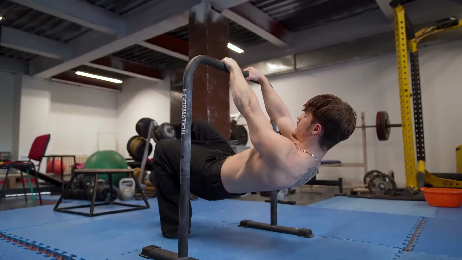 Tuck front lever hold position on a pull-up bar showing proper scapular retraction and body tension