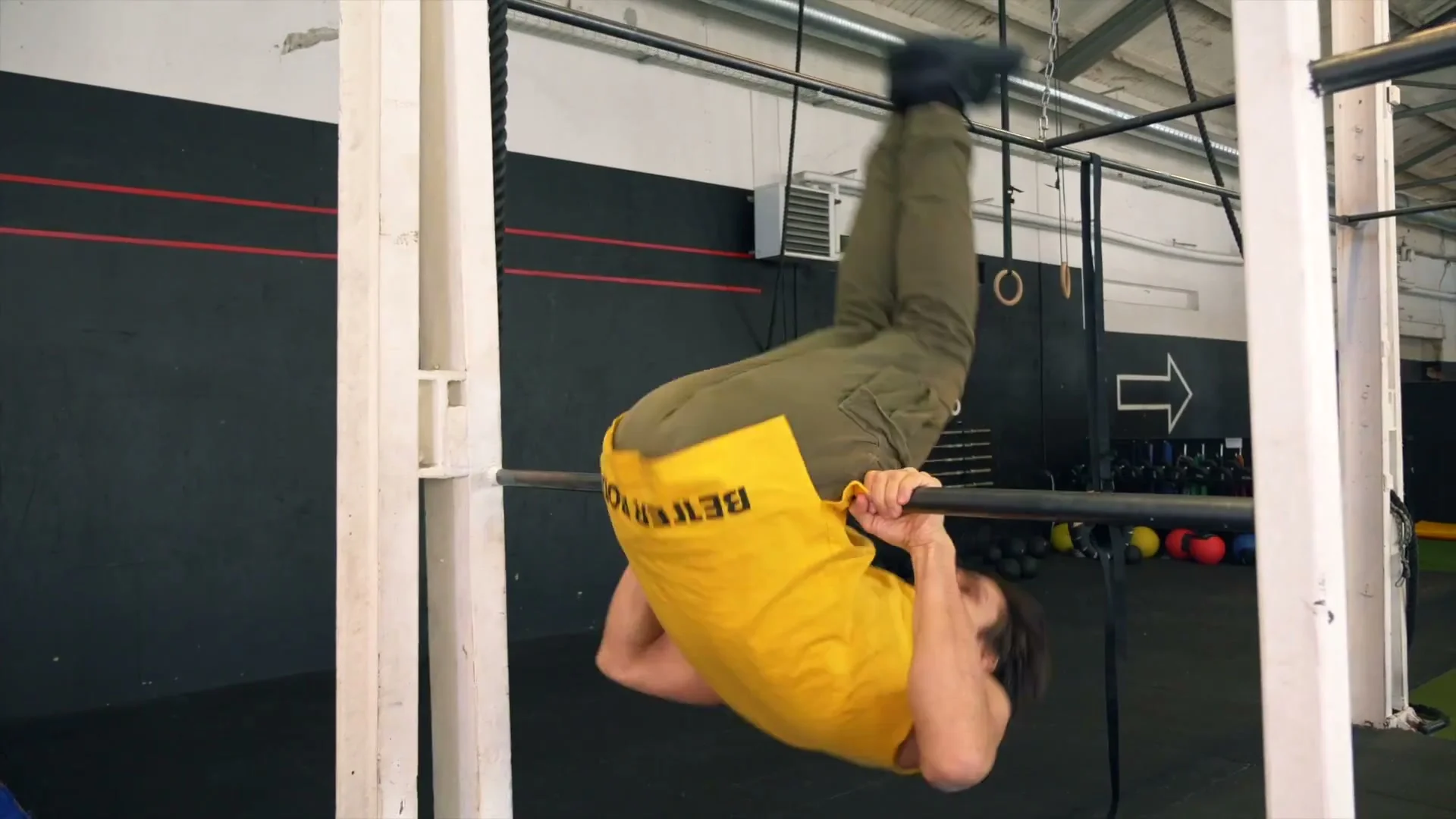 Daniel Flefil demonstrating the upper body dive for the front roll on a low bar: body inverted with bar at hip level, upper body driven forward over the bar