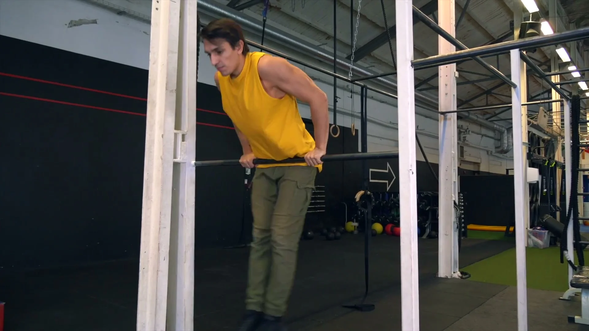 Daniel Flefil at the bar showing the starting position for the heel kick drill: body in straight arm support on a low bar, preparing the heel kick motion