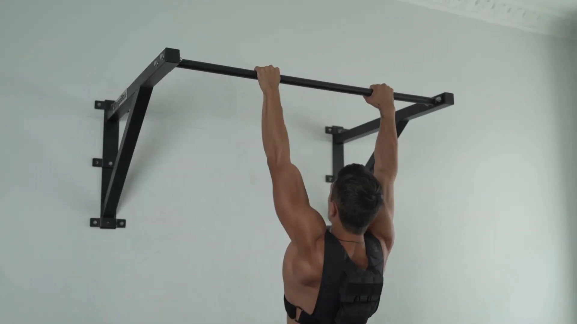 Daniel Flefil performing pull-ups wearing the GORNATION weight vest on a bar
