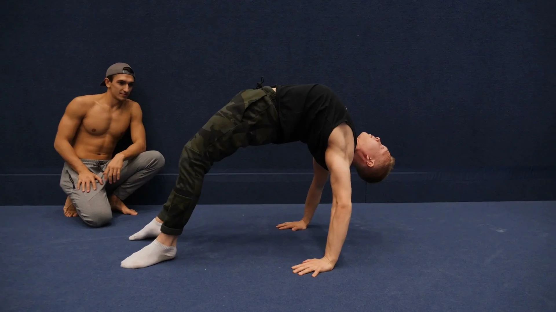 Otto Vainio (OdinMovement) demonstrating the hollowback position: body arched deeply backward from handstand, legs curving over the head