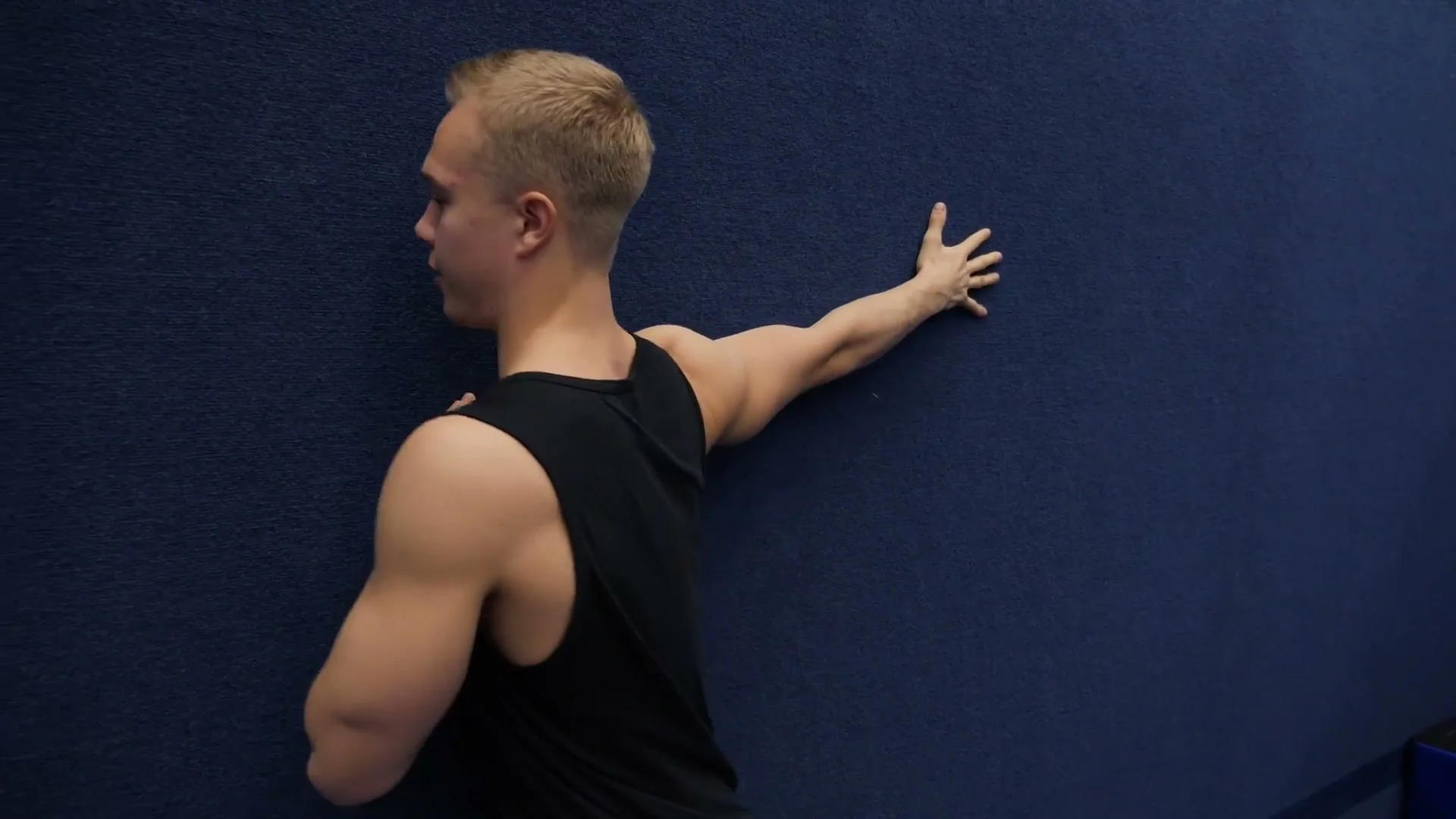 Peg stretch bonus variation: attempting to lift the hand slightly away from the wall to activate upper back muscles, the hollowback-specific activation drill