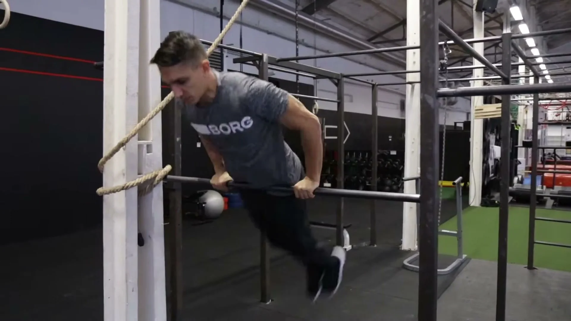 Step 1 of jump on bar: jumping up on a low pull-up bar, leaning forward and bringing legs in front of the bar