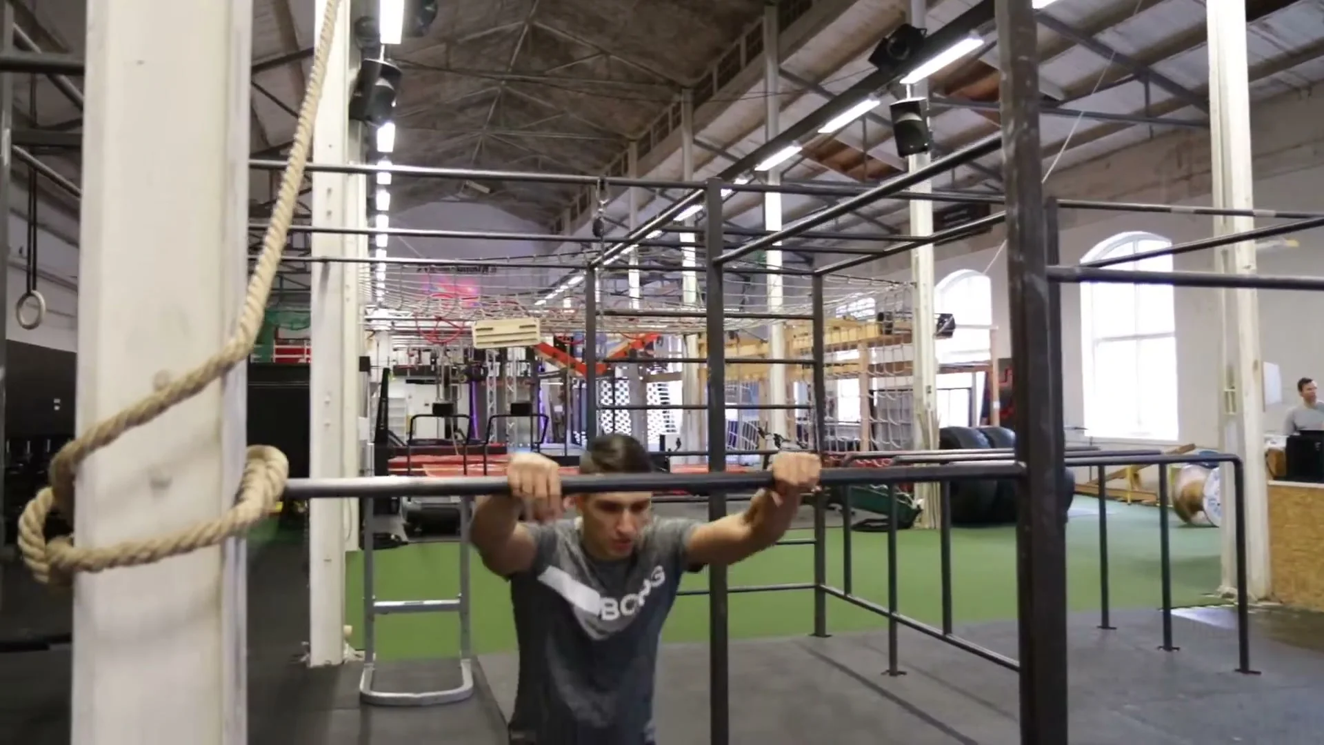 Step 3 of jump on bar: one foot on the bar with both hands released, building confidence for the full bar stand
