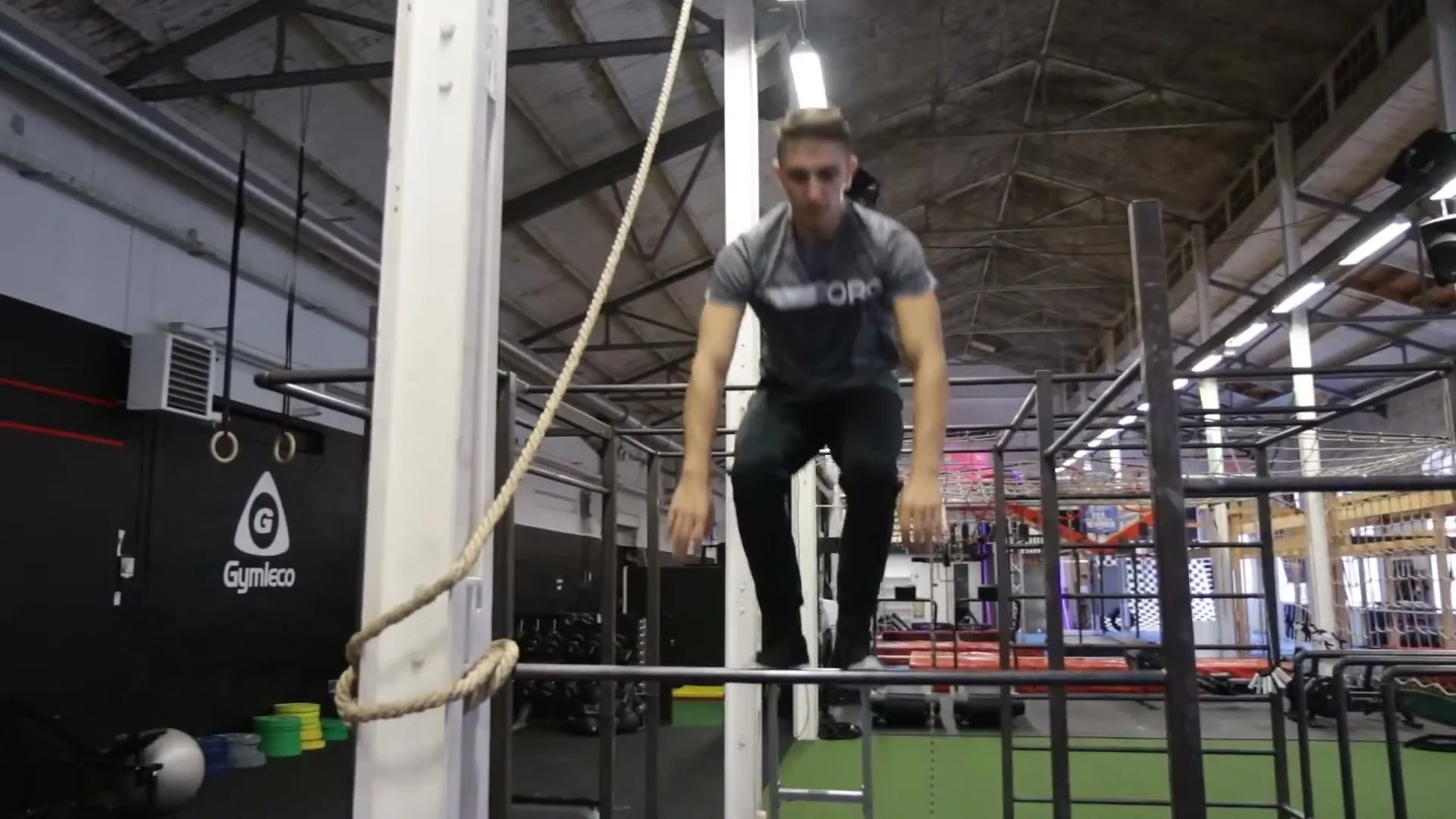 Daniel Flefil standing on top of a pull-up bar at the gym, demonstrating the completed jump on the bar position