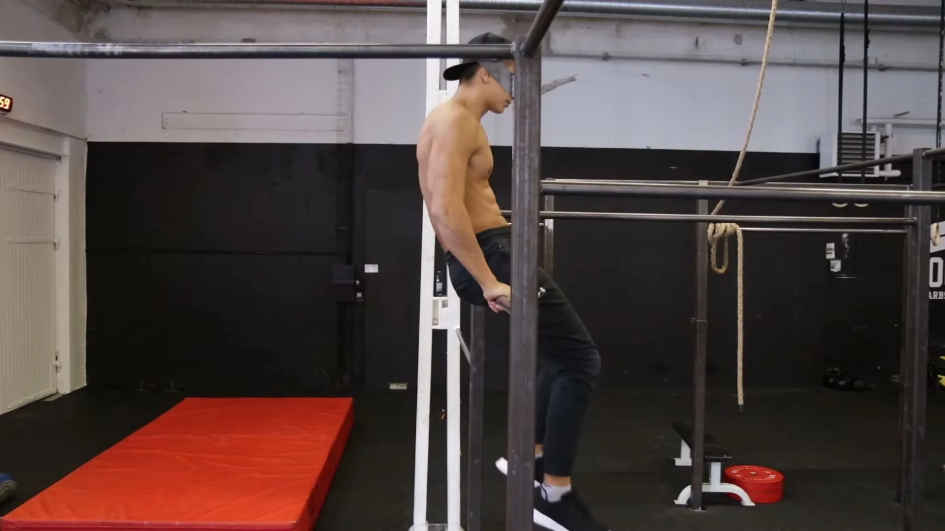 Step 6 of the knee gainer: releasing from a sitting position on top of the bar, the most advanced progression in the knee gainer tutorial