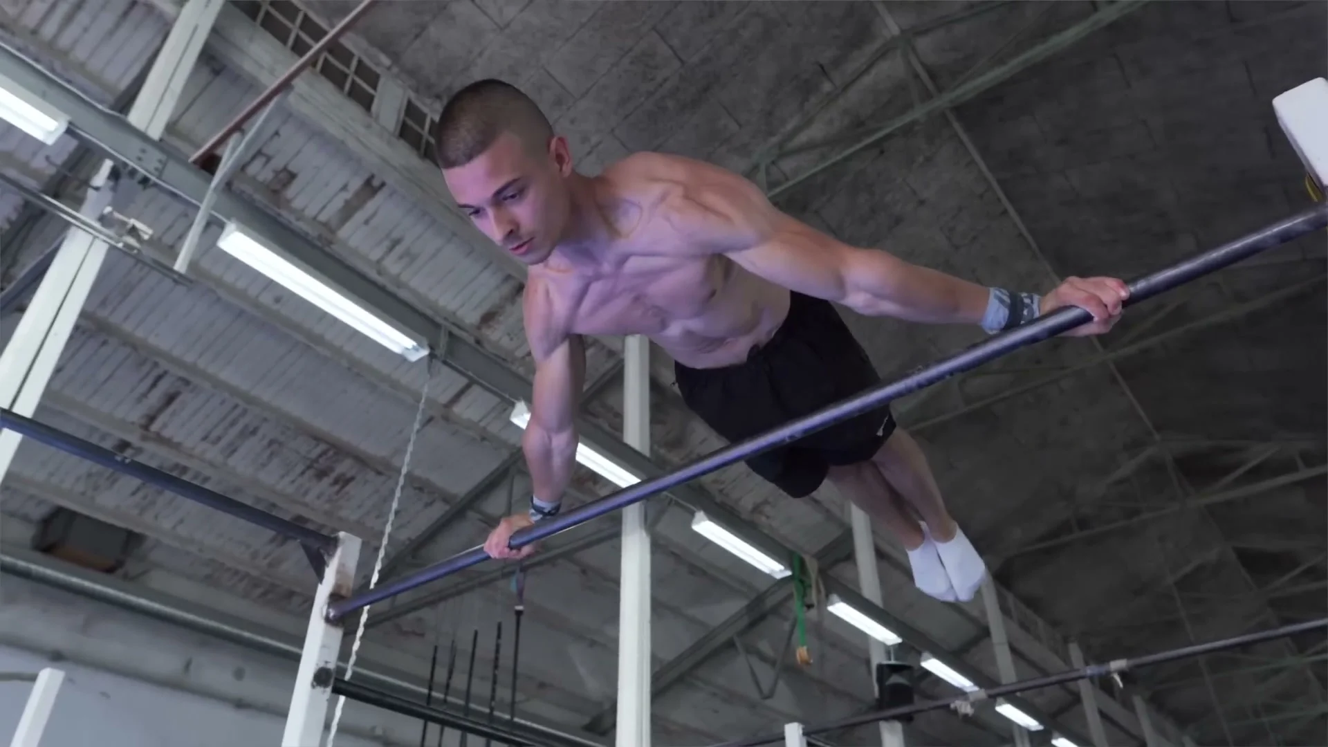 Daniel Hristov holding a full planche on horizontal bars: body fully horizontal with straight arms, demonstrating the finished planche position that the five beginner exercises build toward