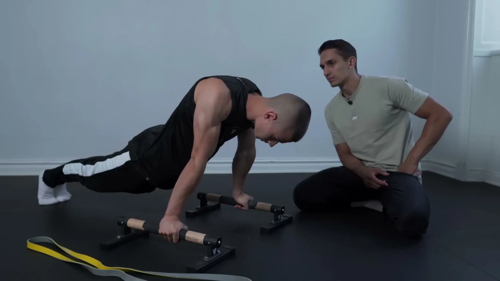 Daniel Hristov performing protraction and retraction push-ups on parallettes with a resistance band for added difficulty: demonstrating the scapula movement pattern critical for planche