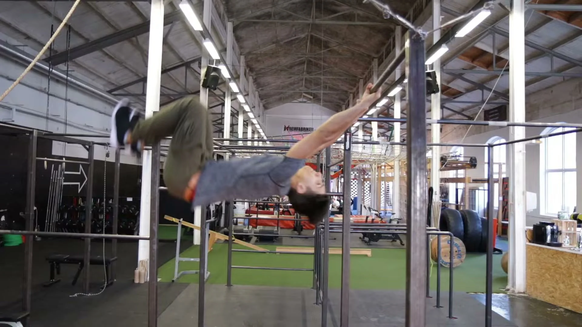 Daniel Flefil in flight during a swing gainer, body extended horizontally after releasing the bar in street workout